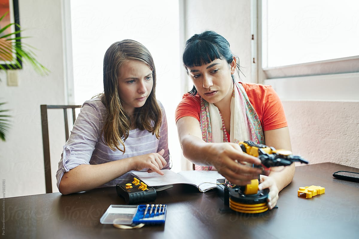 Young woman teaching a teenager robotics