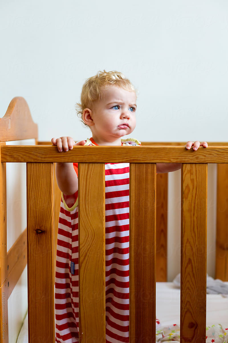 Standing baby in crib in sleep romper after afternoon nap