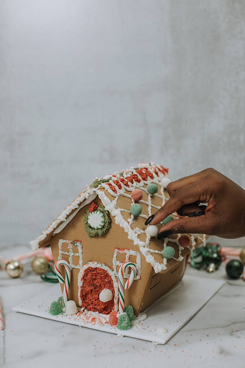 Woman Decorating Gingerbread House with Candy
