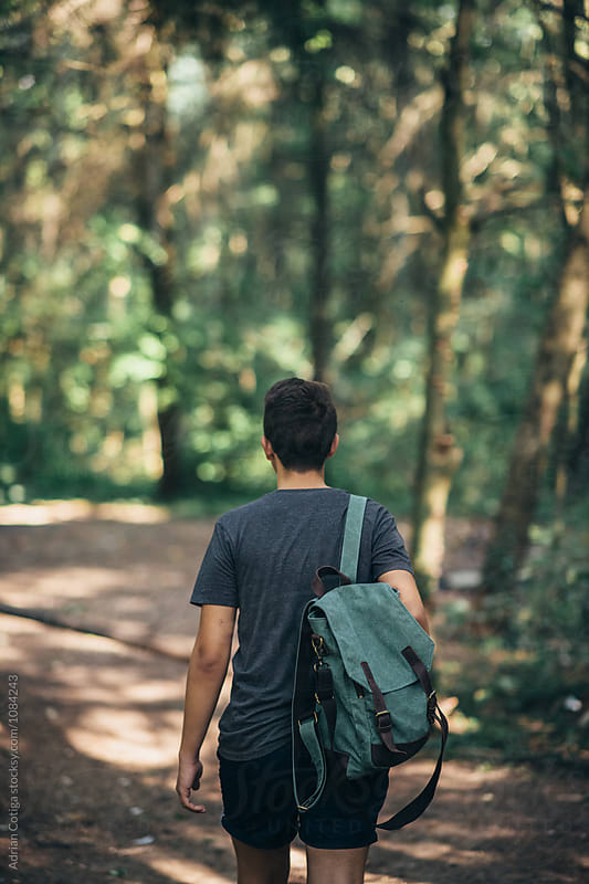 Young teen boy with a backpack exploring the forest