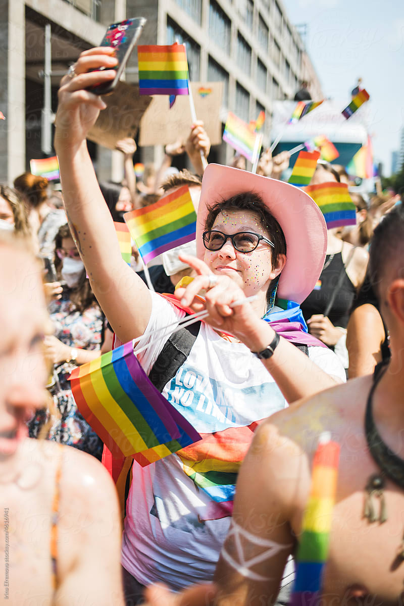 Woman in a pink cowboy hat taking a photo in a pride crowd