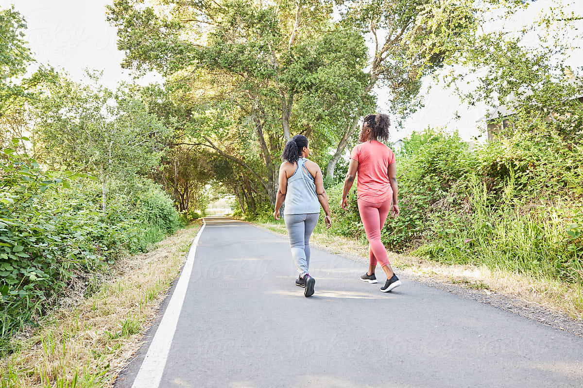 Black girlfriends walking and talking together on nature park trail