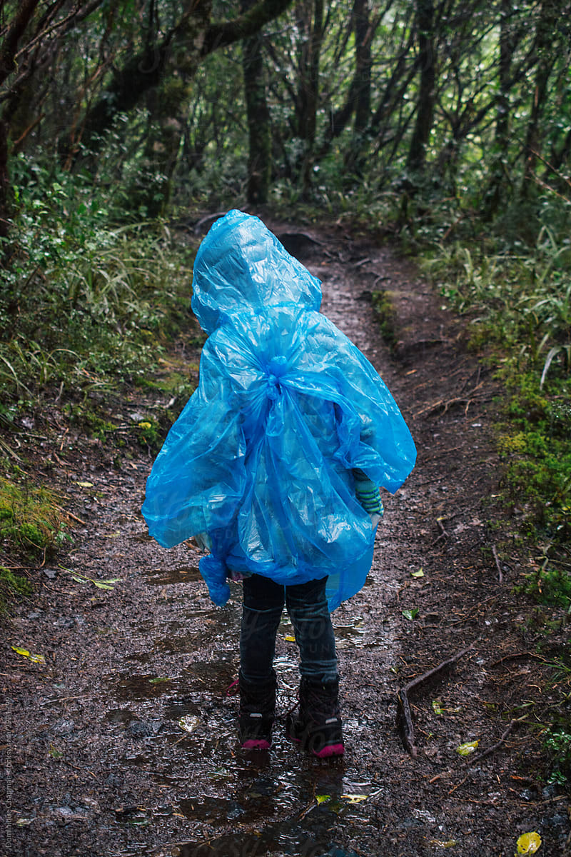 Young girl hiking through the rain with bright blue poncho