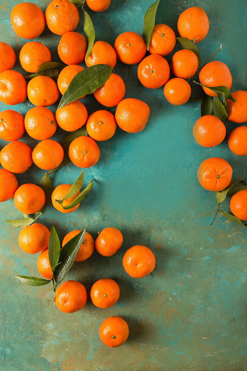Fresh ripe tangerines with green leaves on a turquoise abstract background