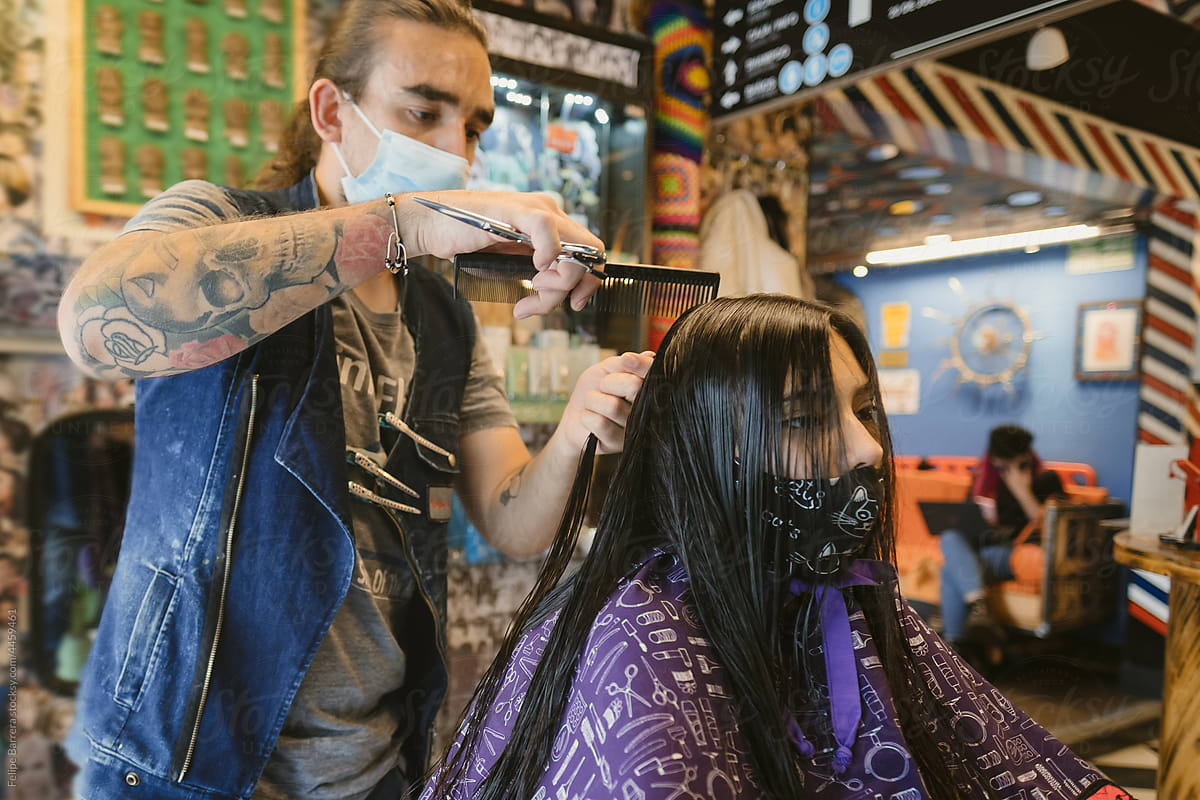 Tattooed male hairdresser providing a haircut