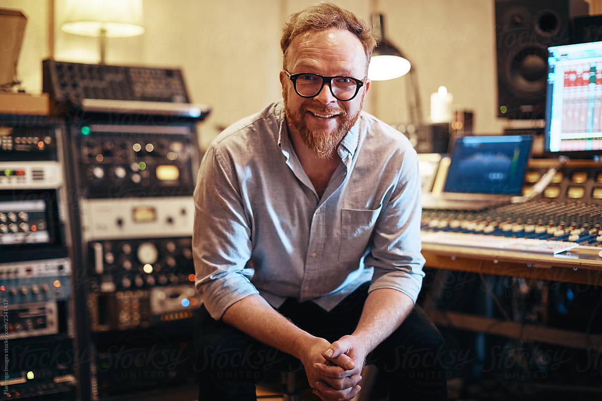 Music producer smiling while sitting in his recording studio
