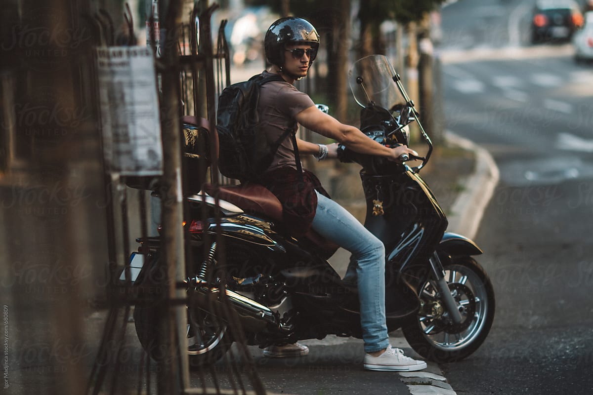 young man on a motorcycle, driving  on the sidewalk, ready to ride