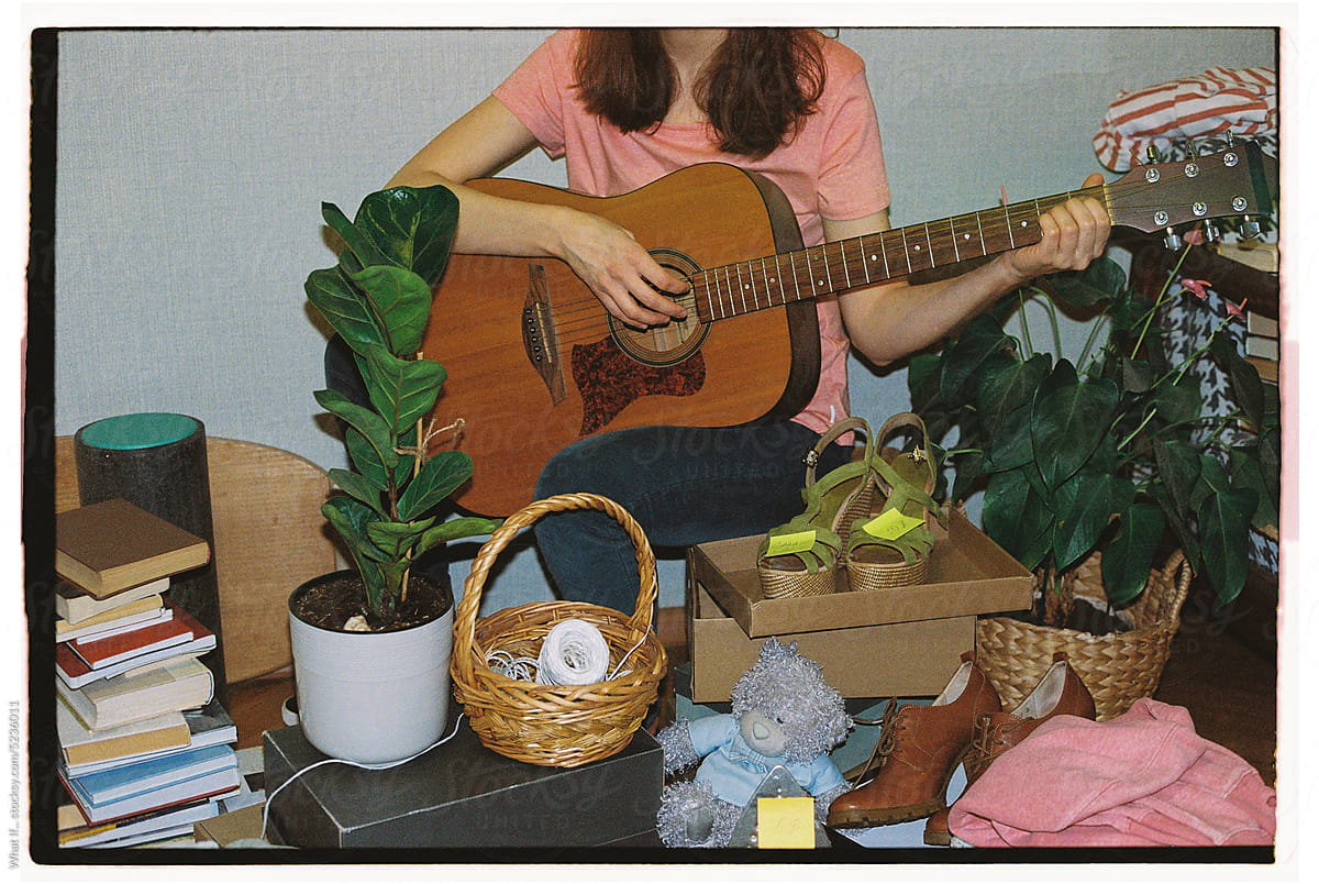 An unrecognizable woman plays guitar at a second hand market.