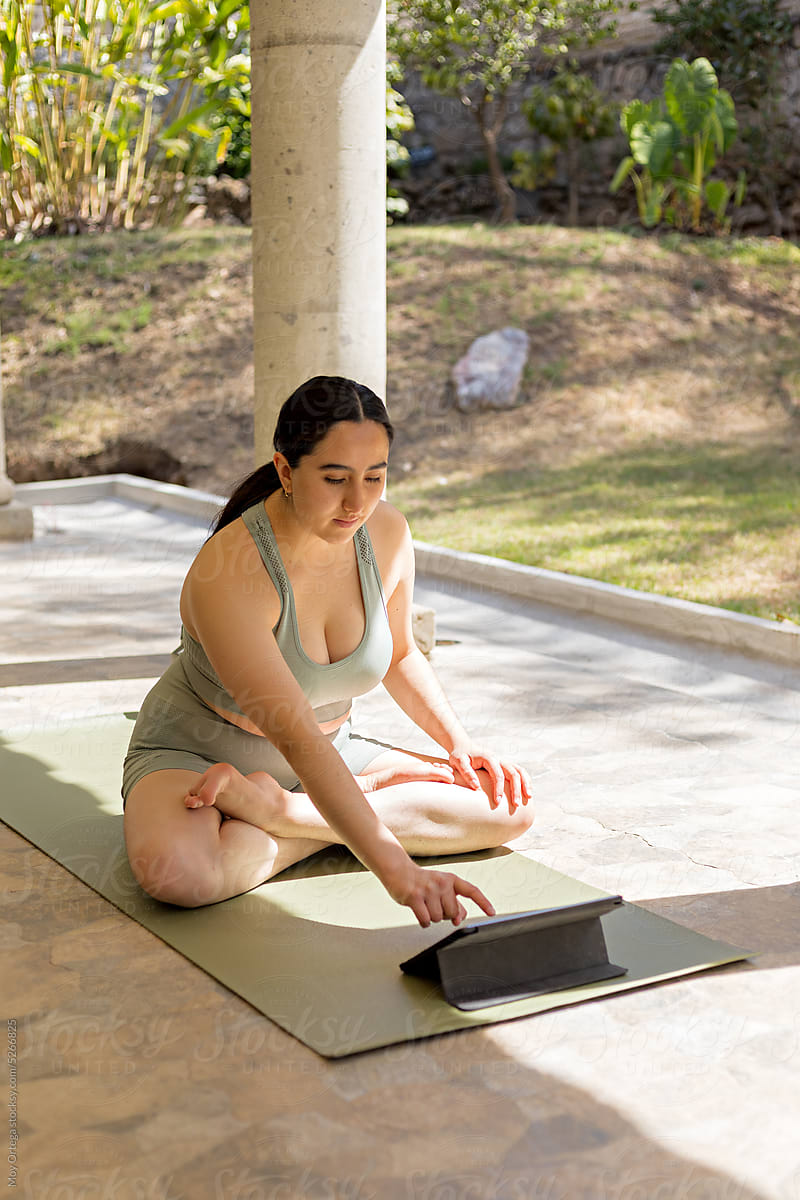 Woman Using A Tablet To Exercise In Her Backyard