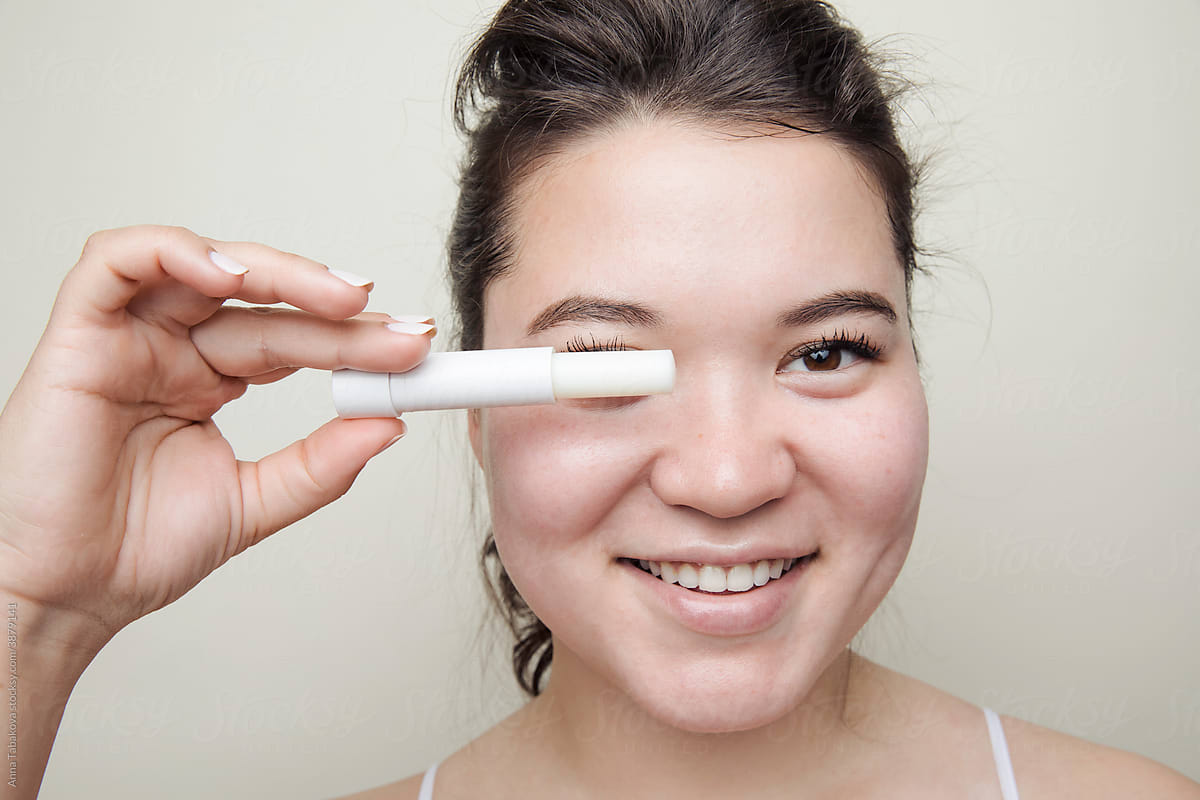 Eastern asian woman holding a lip balm smiling
