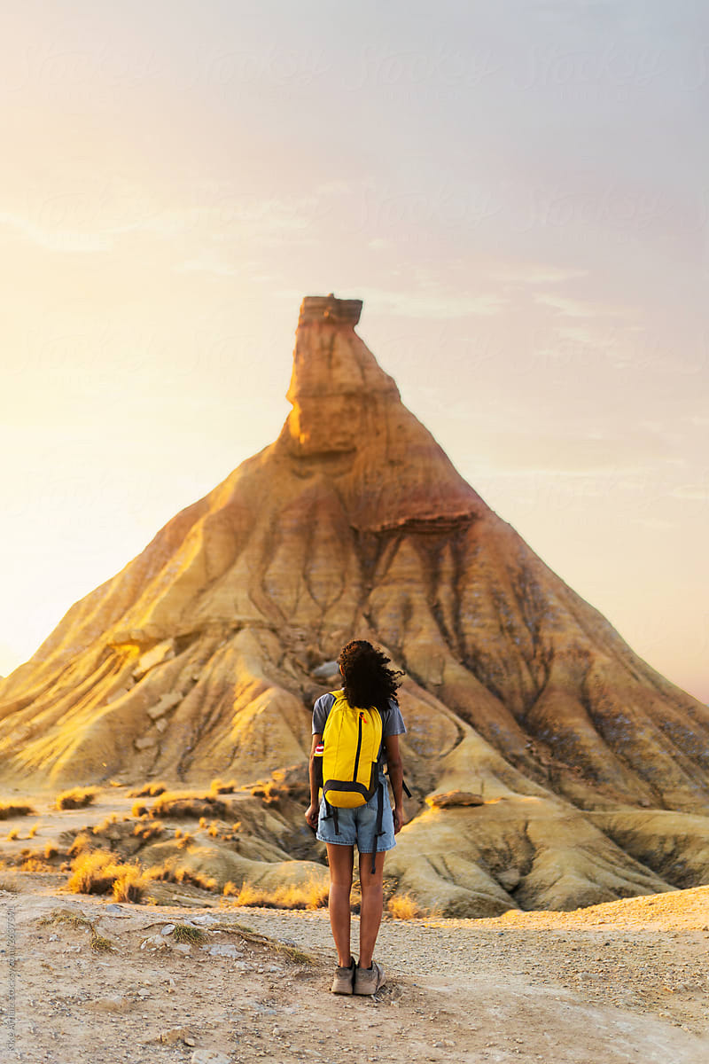 rear view of a woman with a yellow backpack in the desert of the Bardenas. Navarra