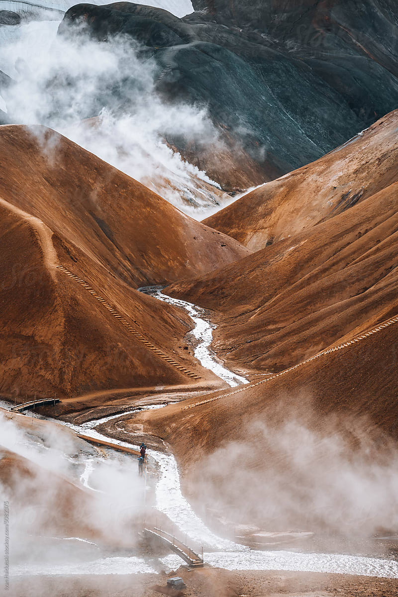 Hiker exploring golden brown landscape of Iceland\'s geothermal area.