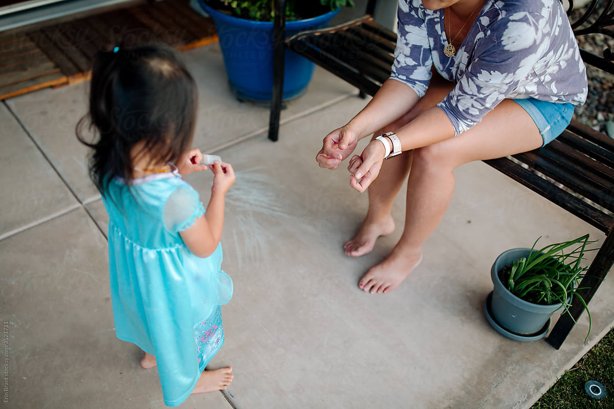 Barefoot mom and young daughter on patio
