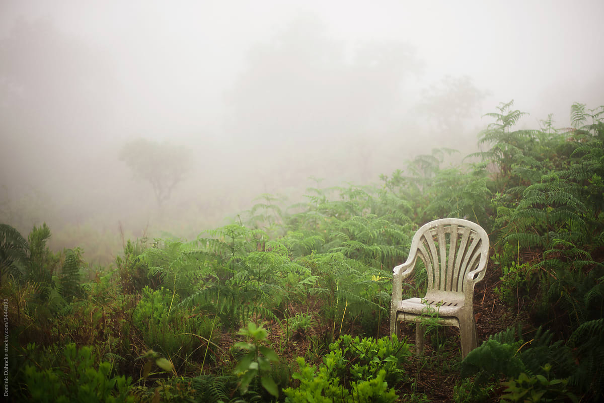 Two plastic chairs abandoned in middle of the fog.