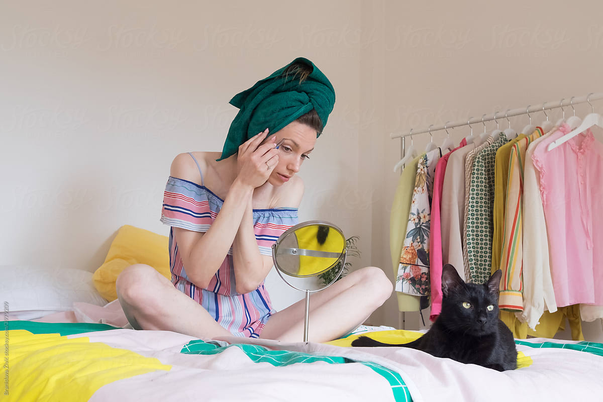 Female model having a selfcare day in her bedroom with black cat