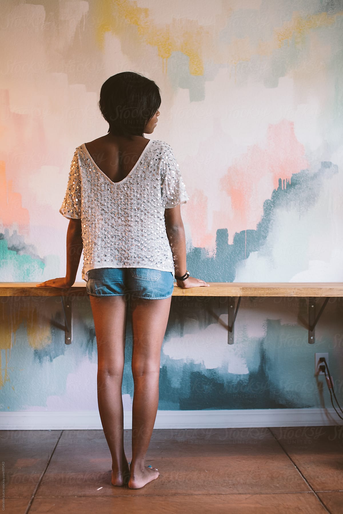 Black girl standing at desk in front of a painted wall