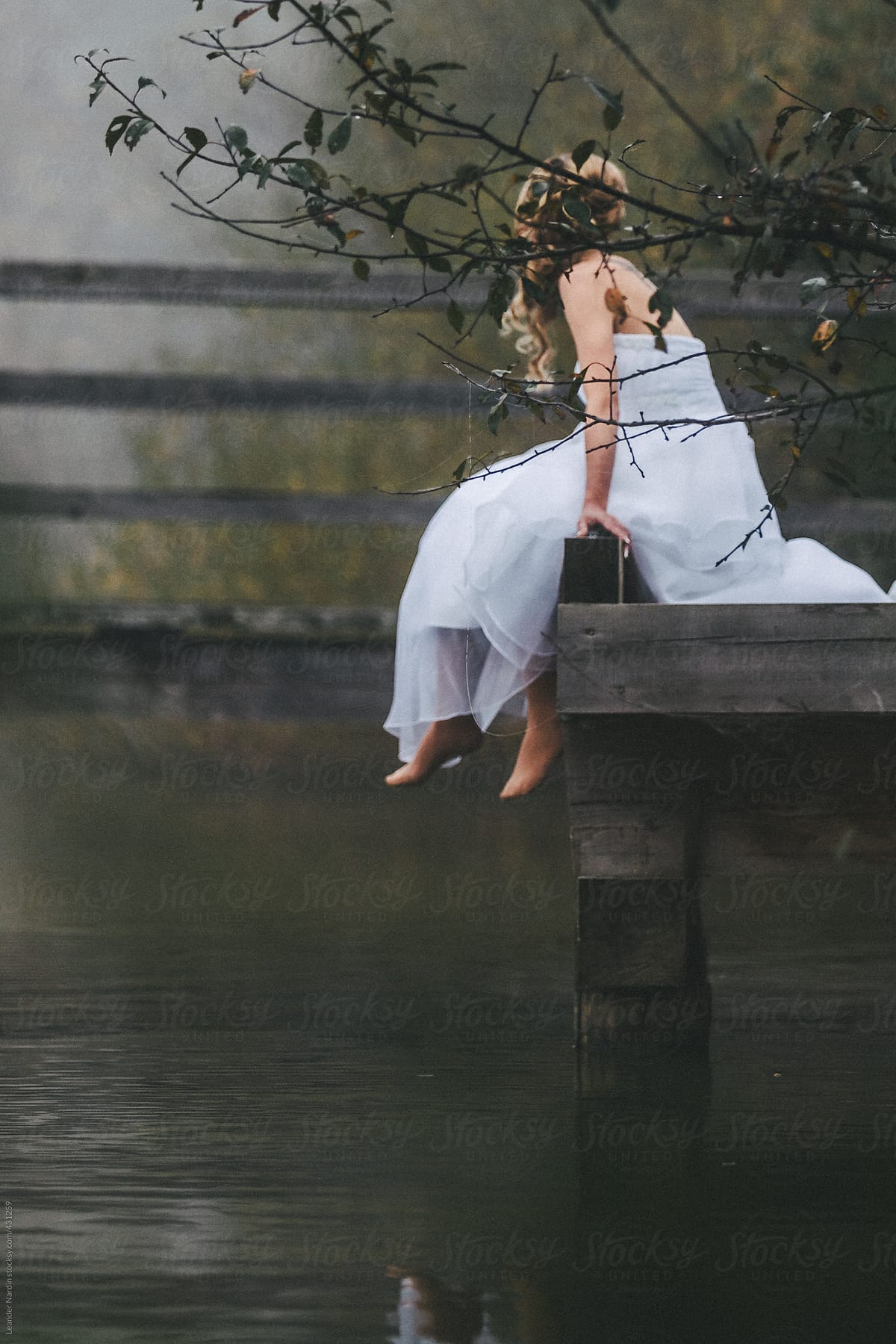 Barefoot Bride In Beautiful White Wedding Dress Sitting On A Jetty In