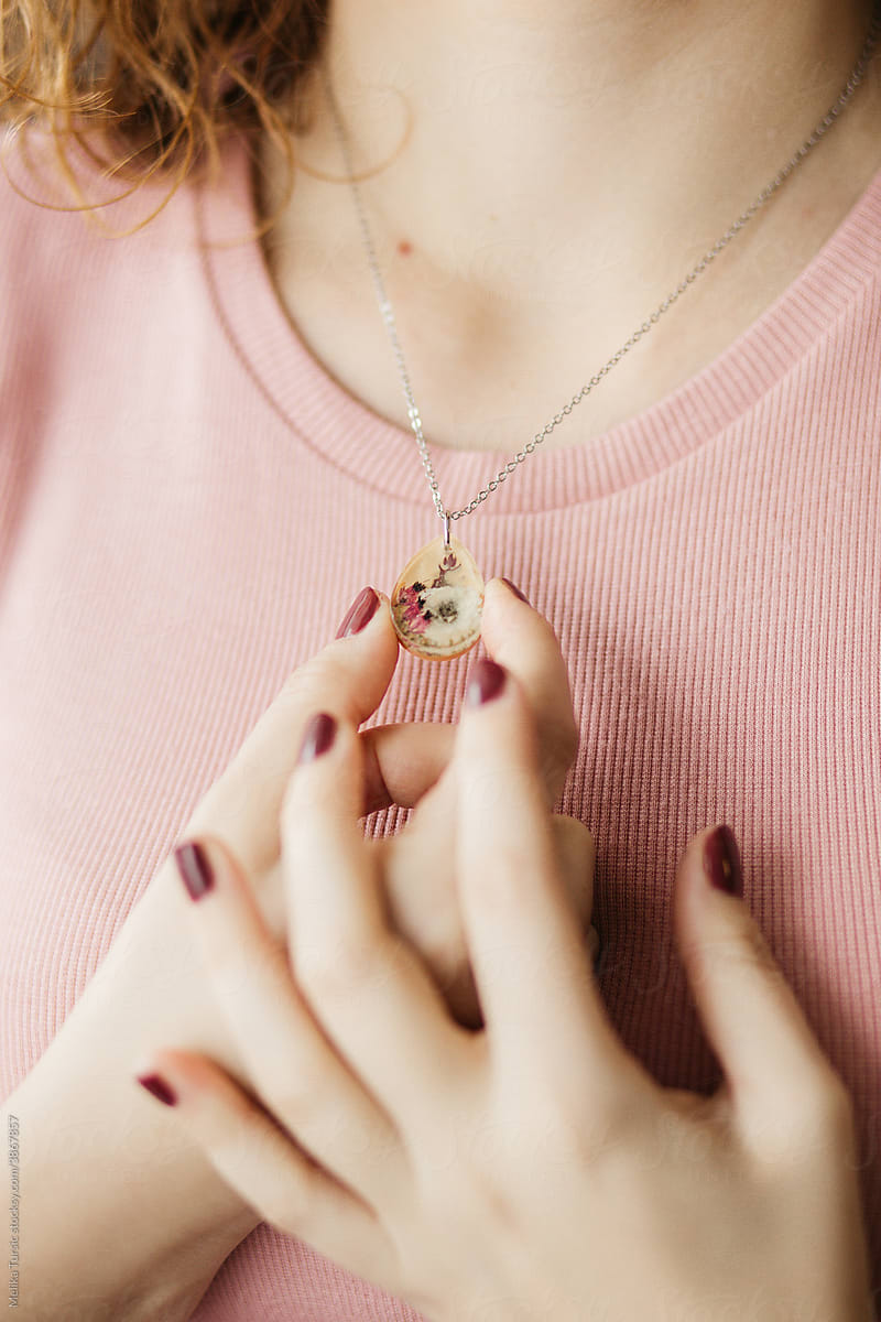 Close up of female hands holding floral epoxy necklace