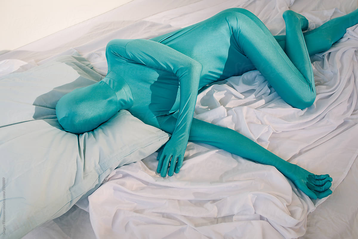 Anonymous person in odd colorful wear lying on bed