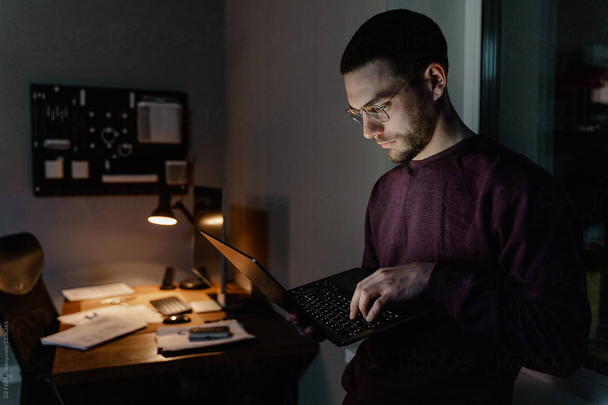 A man uses a laptop in the office at night