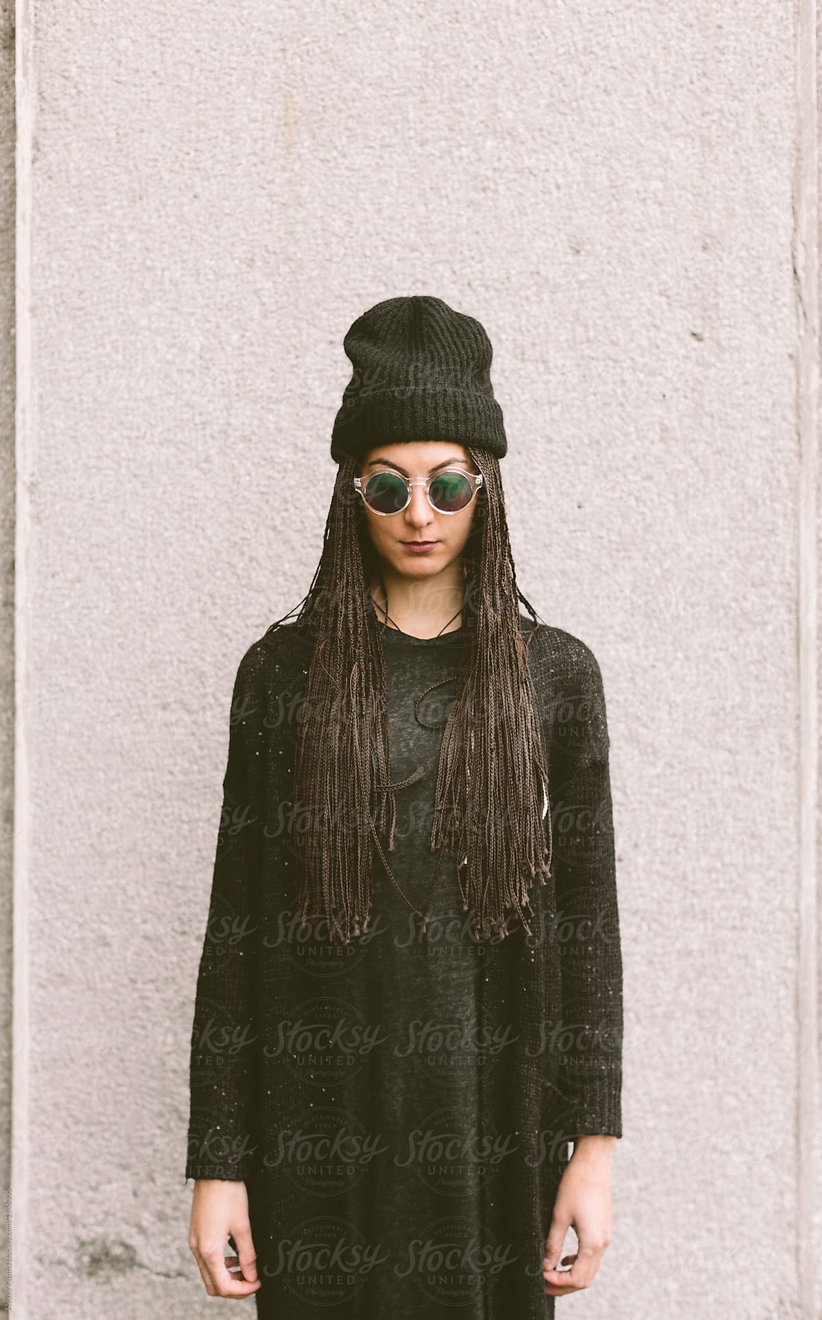 young woman wearing a black wool hat and round sunglasess