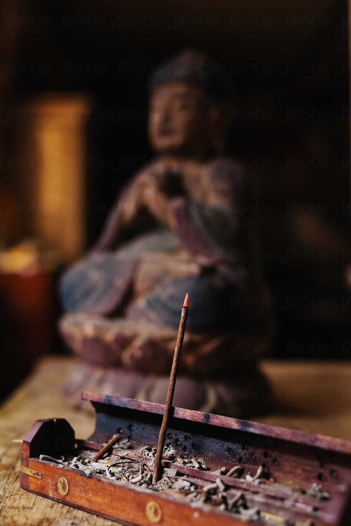 Incense sticks and old statue of Buddha