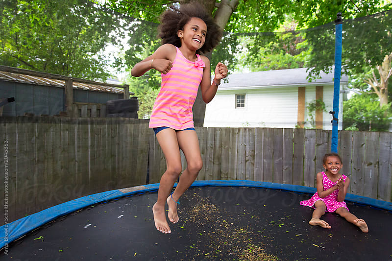 A Young Girl Jumping In A Large Trampoline.