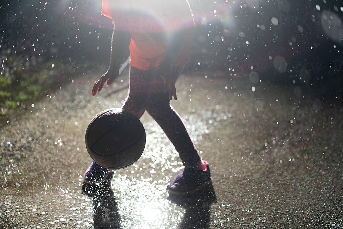 child dribbles basketball in the rain
