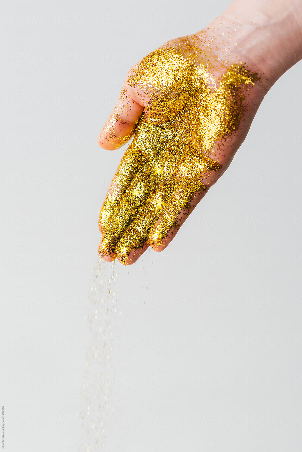 Glitter falling from hand covered in golden glitter