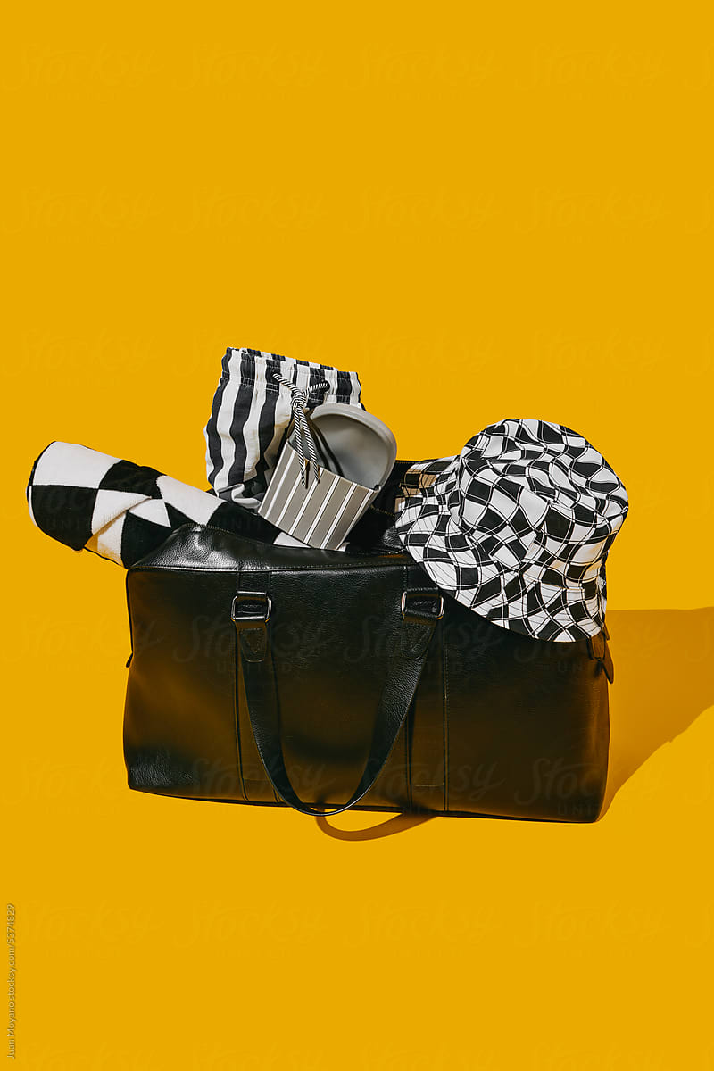 black travel bag with many black and white summer items