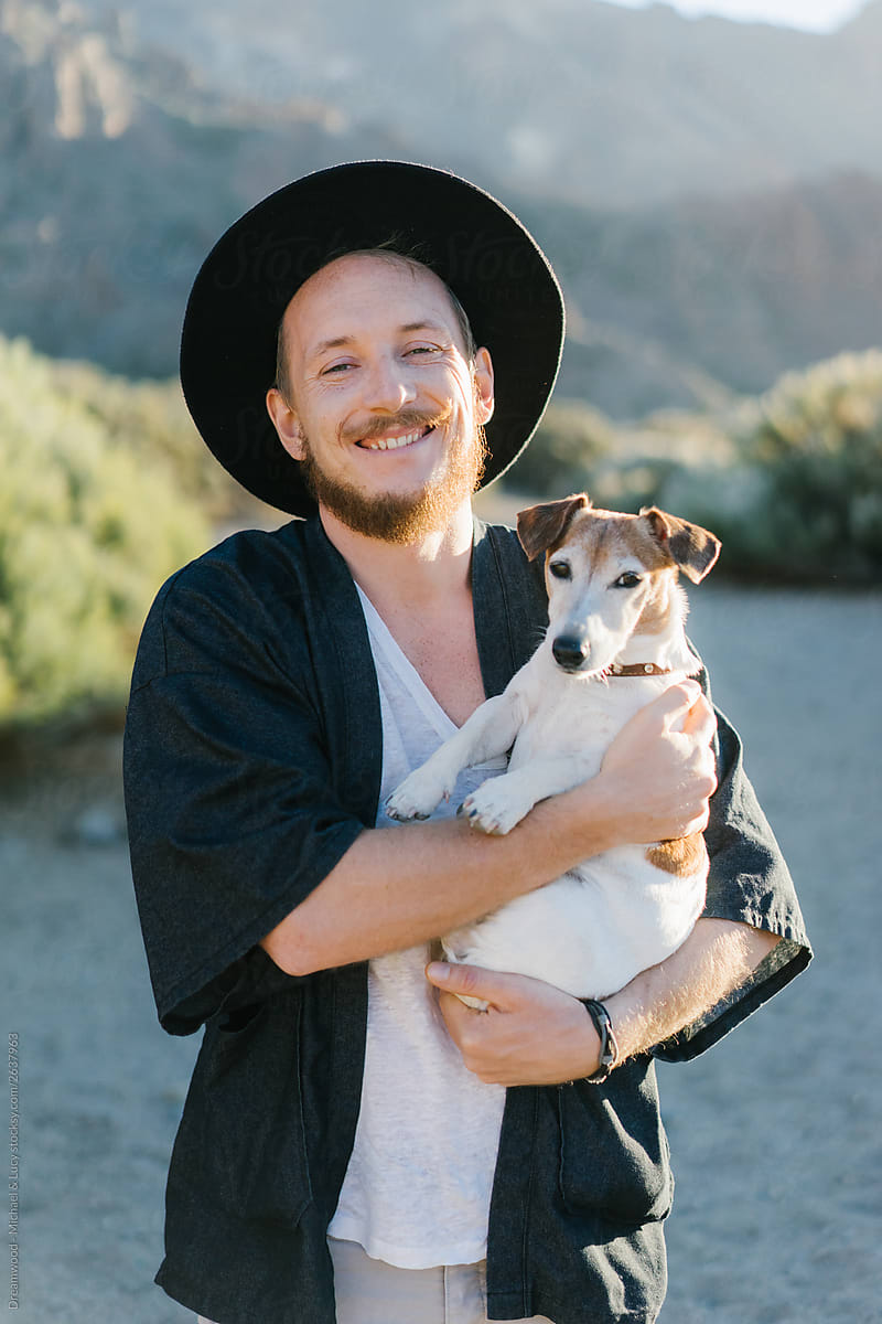 Smiling adult man and pretty dog in desert
