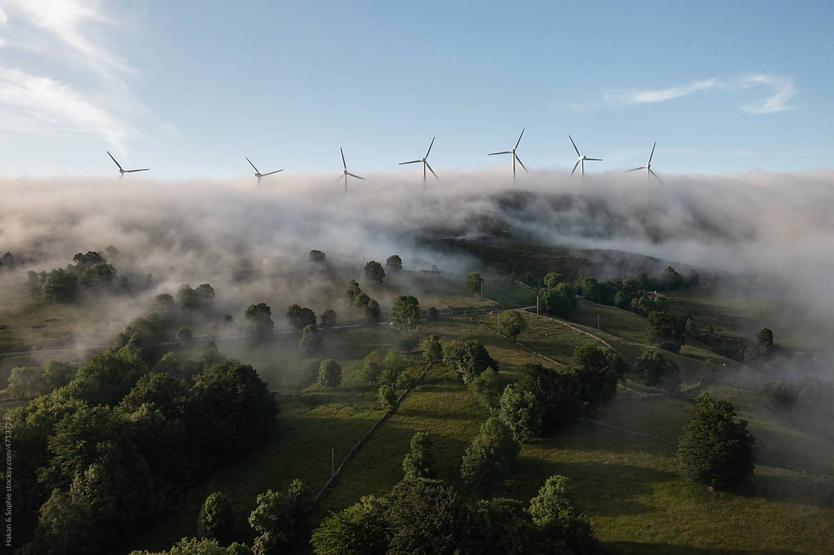 foggy pastures with windmills above the clouds