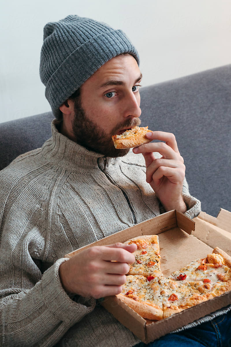 Modern male eats pizza.