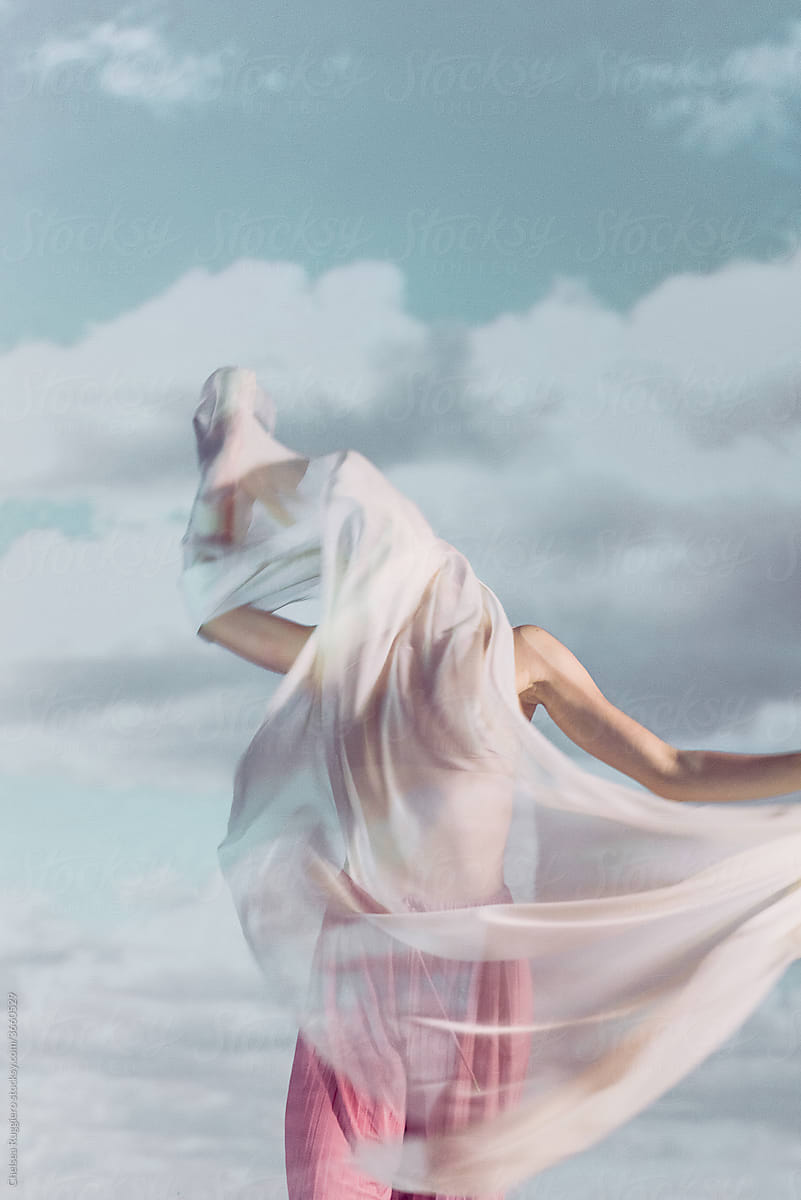 Person wrapped in fabric with clouds behind her
