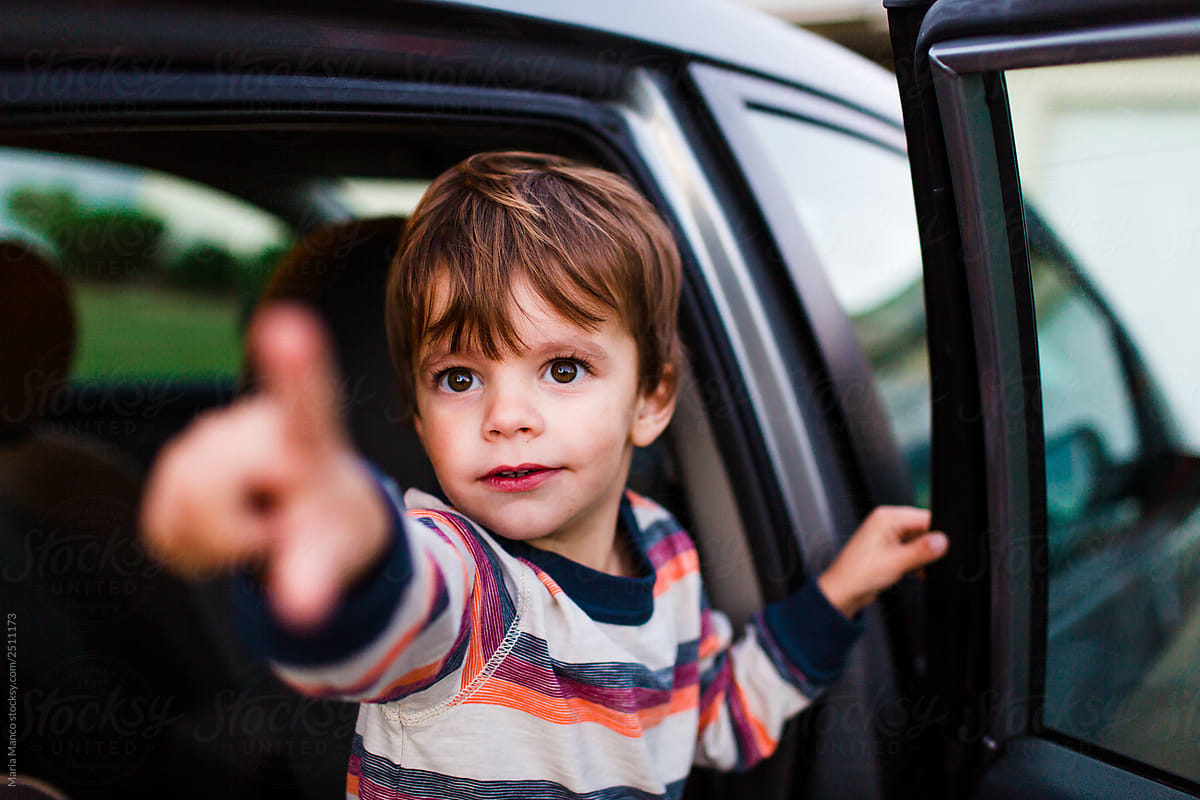 boy in car points at something