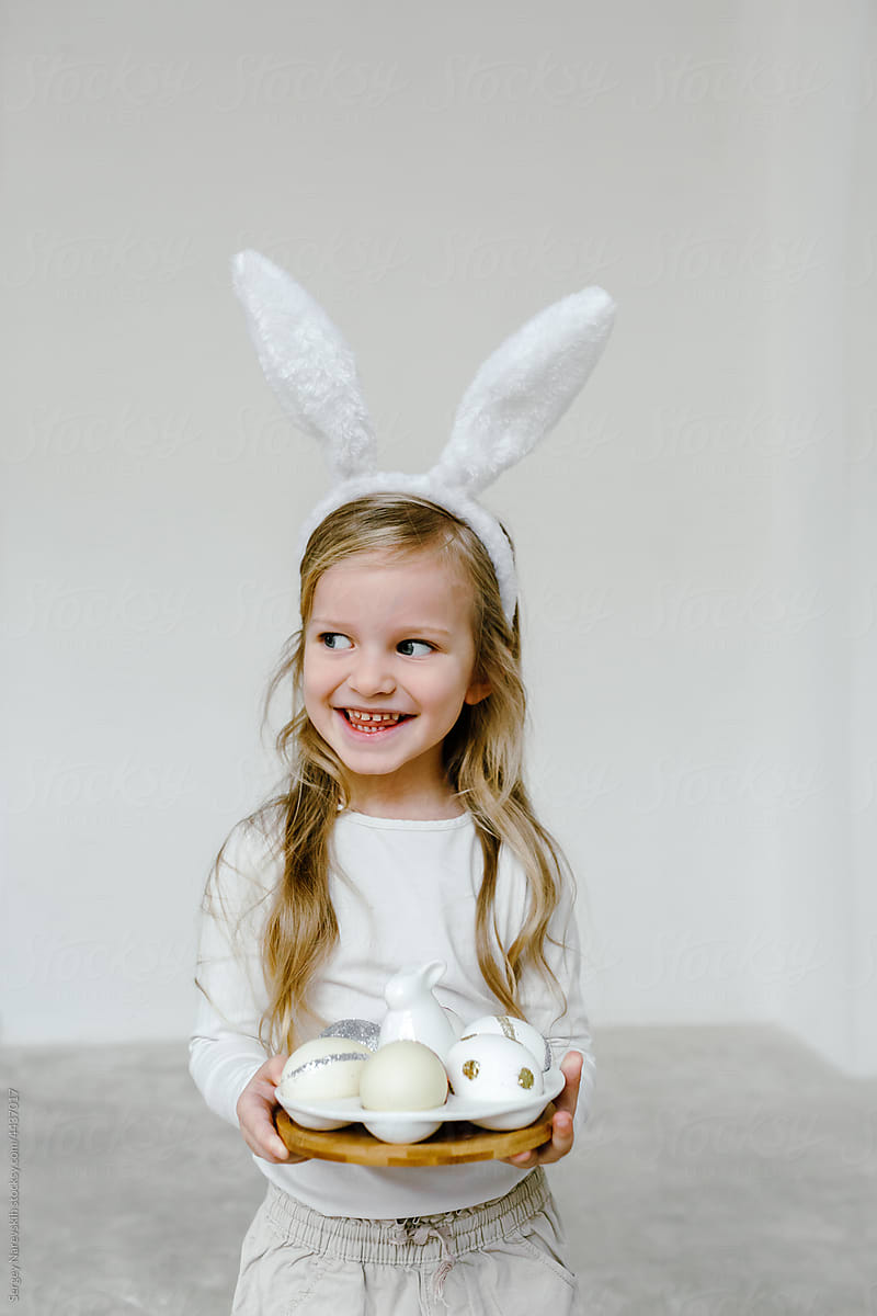 Smiling kid in bunny ears with Easter eggs