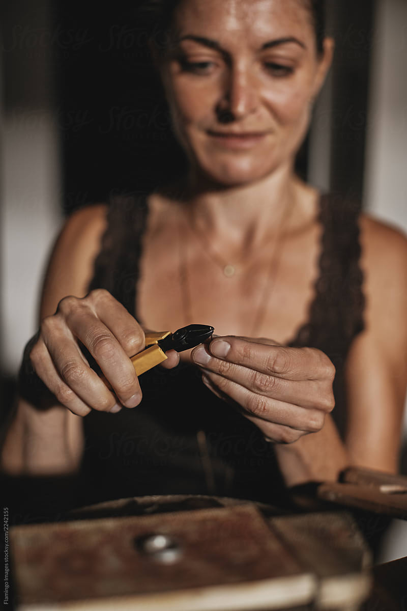 Female jeweler shaping a ring with pliers in her studio