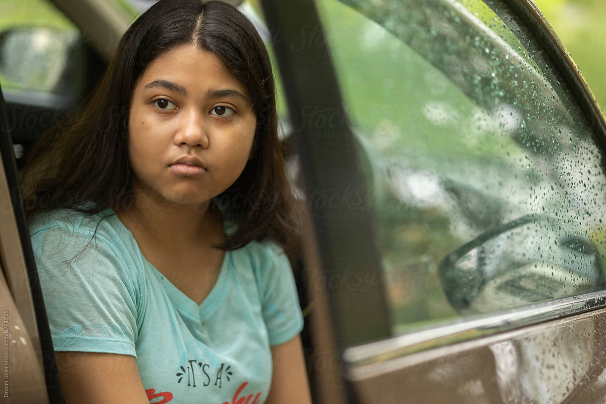Teenage Indian girl sit inside car and in somber mood
