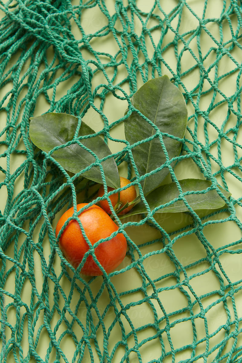 Natural tangerine inside string bag, close-up.
