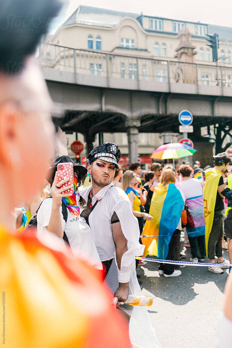 Man in shiny police hat posing for selfie at a Pride