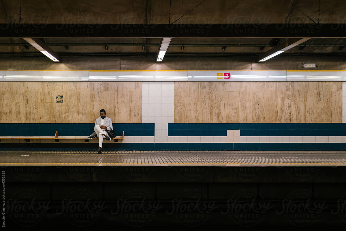 Man sitting alone on underground platform bench
