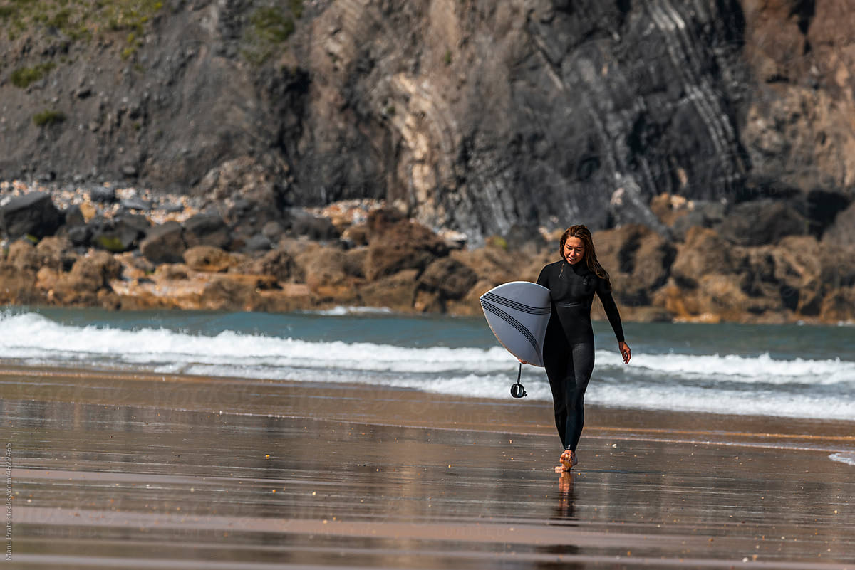 Sportswoman with surboard walking on beach