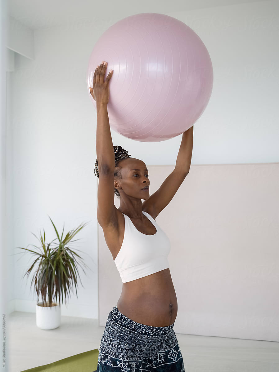 Fit woman carrying baby lifting exercise ball