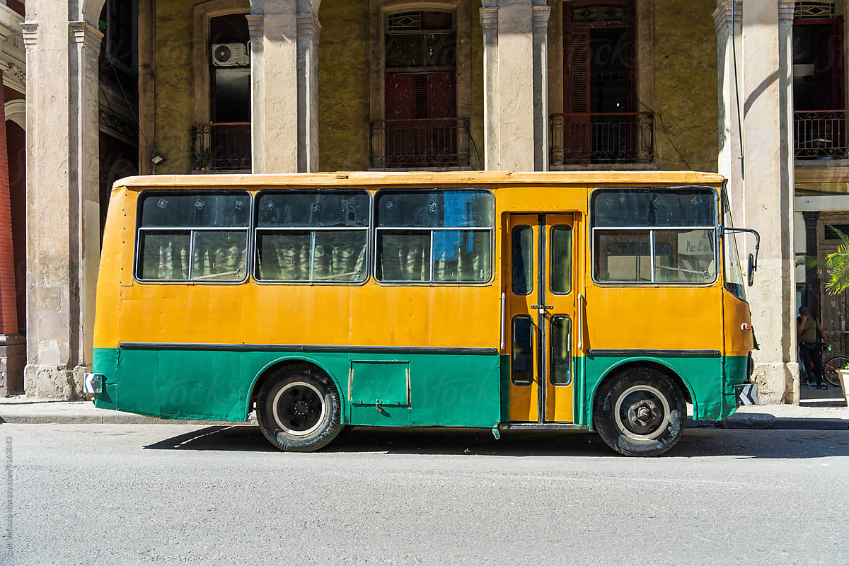 Old Yellow And Green Bus Parked In Front Of A Building.
