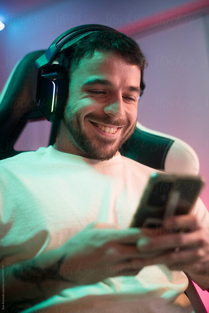 Smiling young man texting on phone with headset