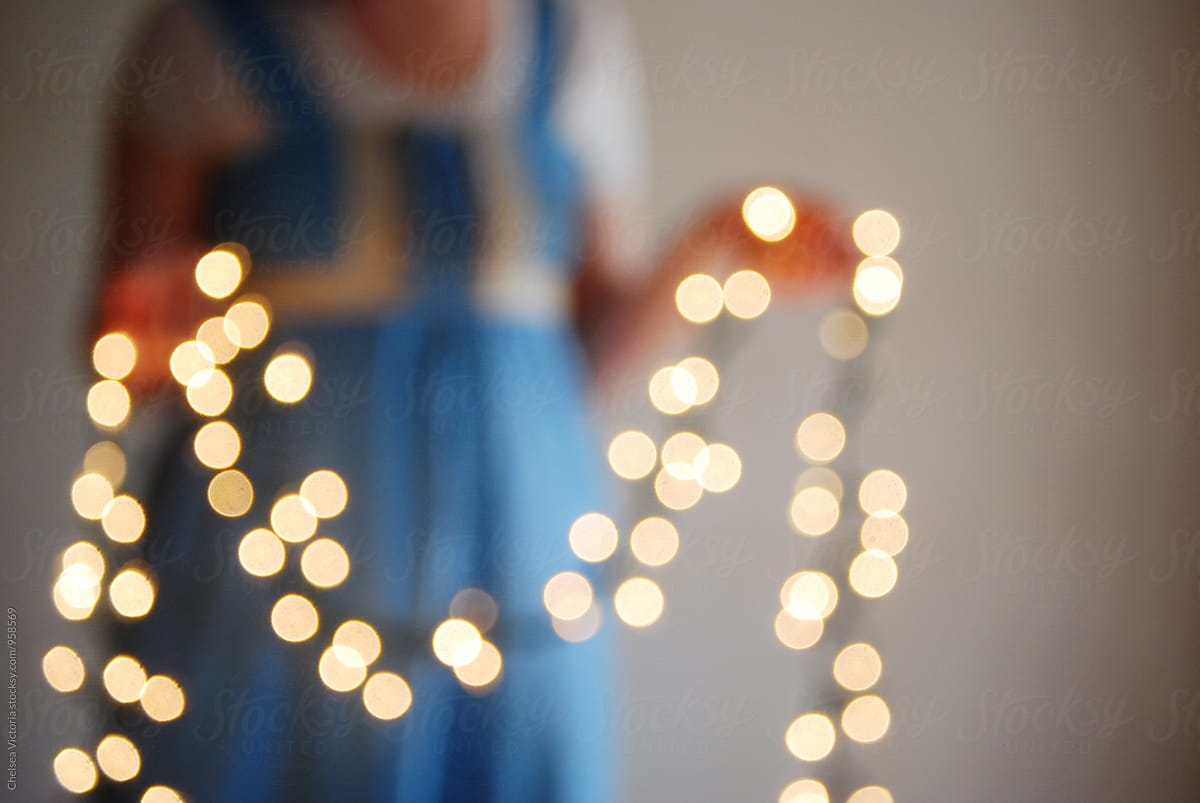 A woman holding out of focus twinkle lights