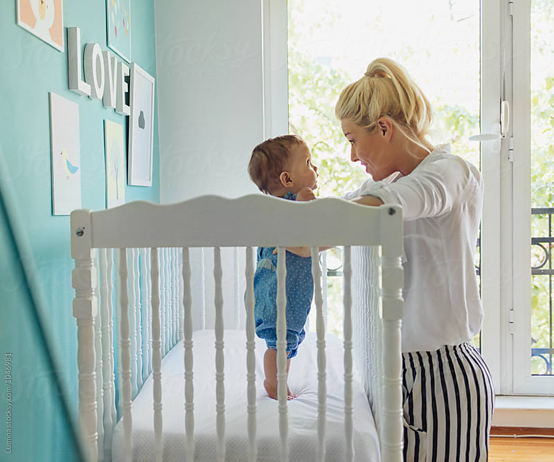 Woman Holding a Baby Girl in Her Crib
