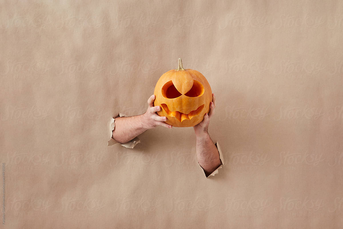 Halloween pumpkin held by female hands.