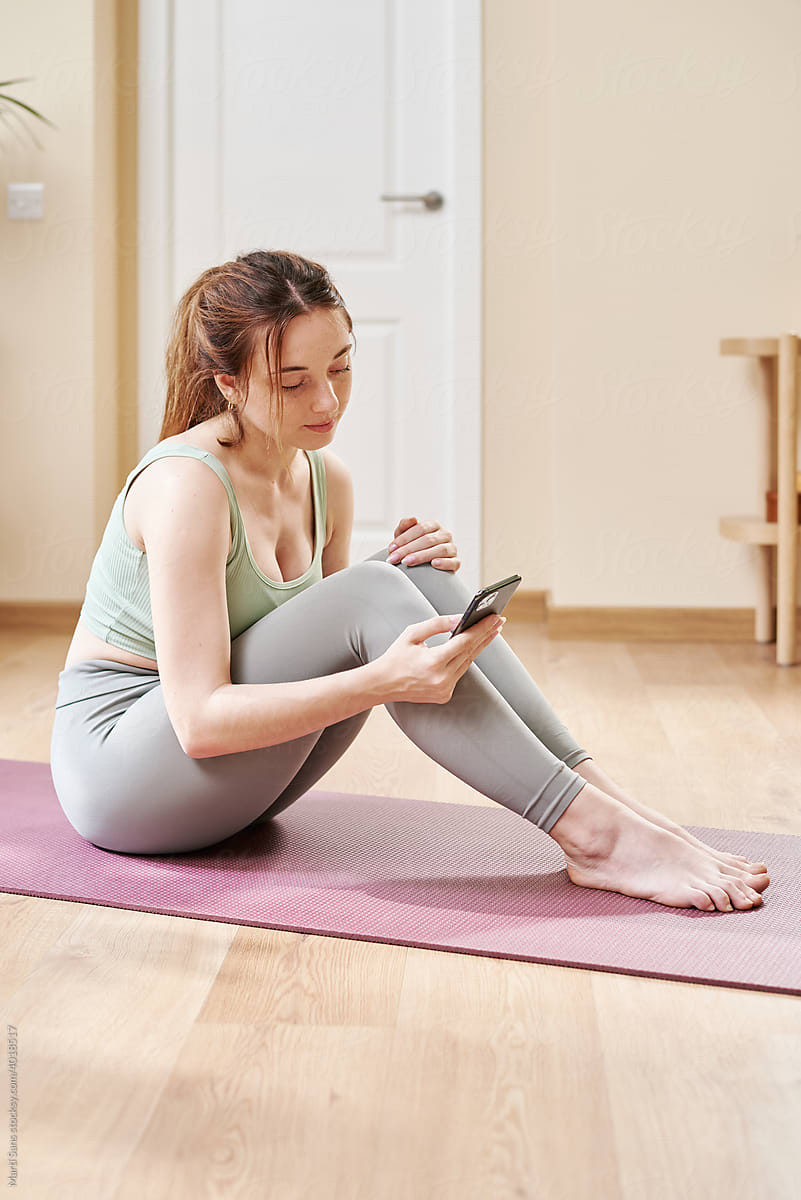 Sportswoman using mobile phone during home workout