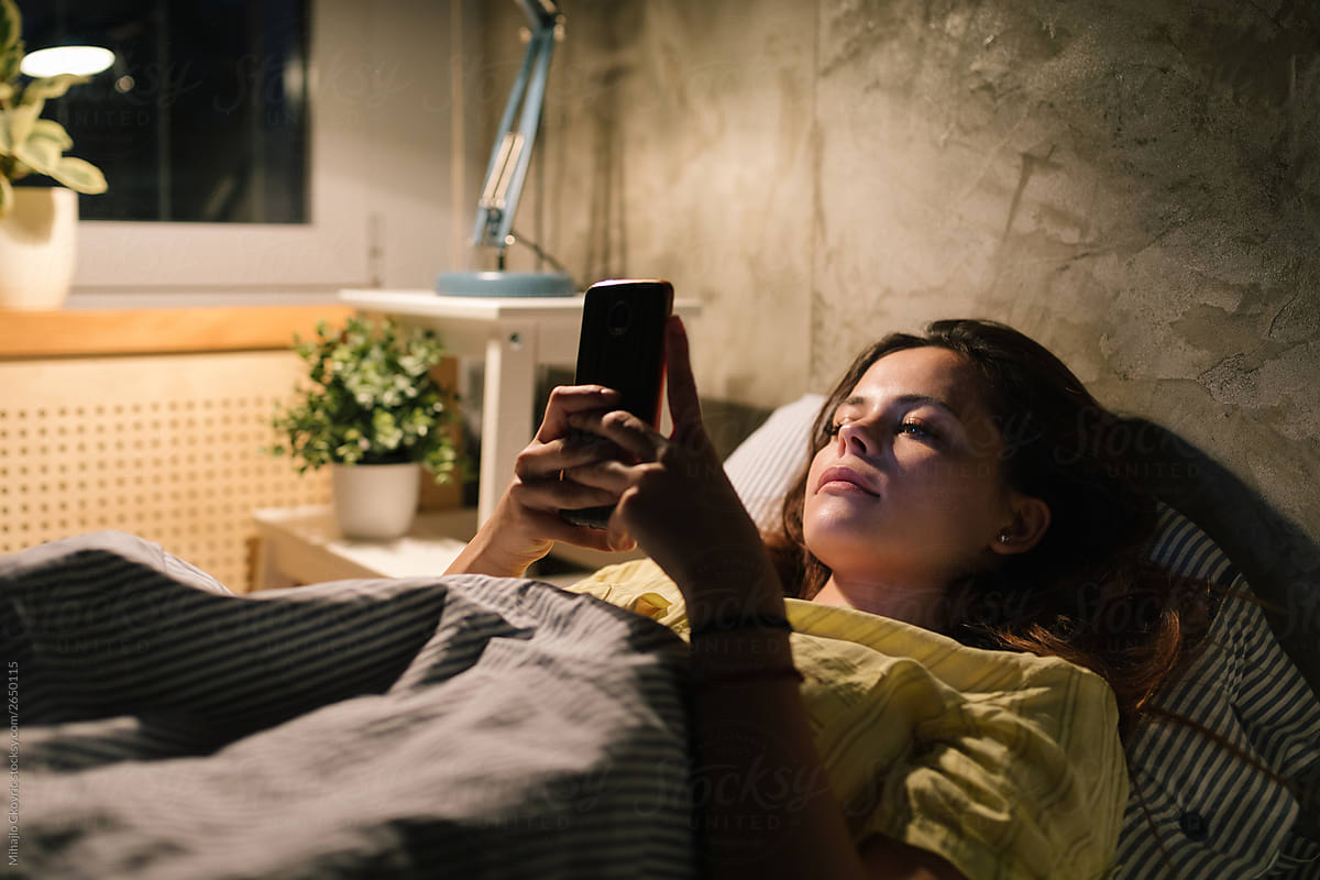 Young Woman Using Her Phone In Bed By Stocksy Contributor Mihajlo Ckovric Stocksy